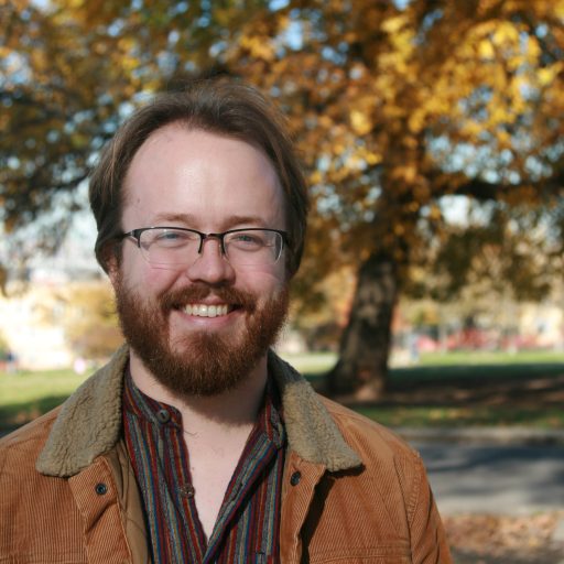 Head and shoulders of the author, gold-leaved tree leaning in the background
